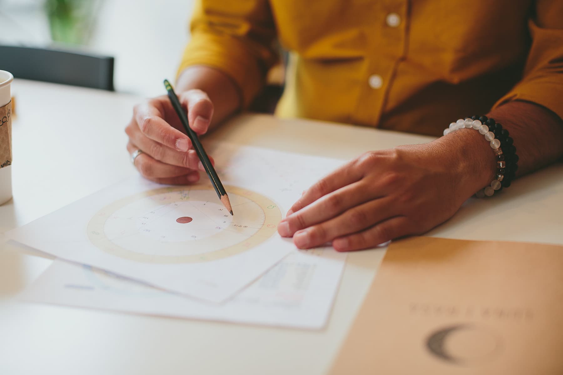 Hand pointing a pencil at a printed birth chart wheel during a reading