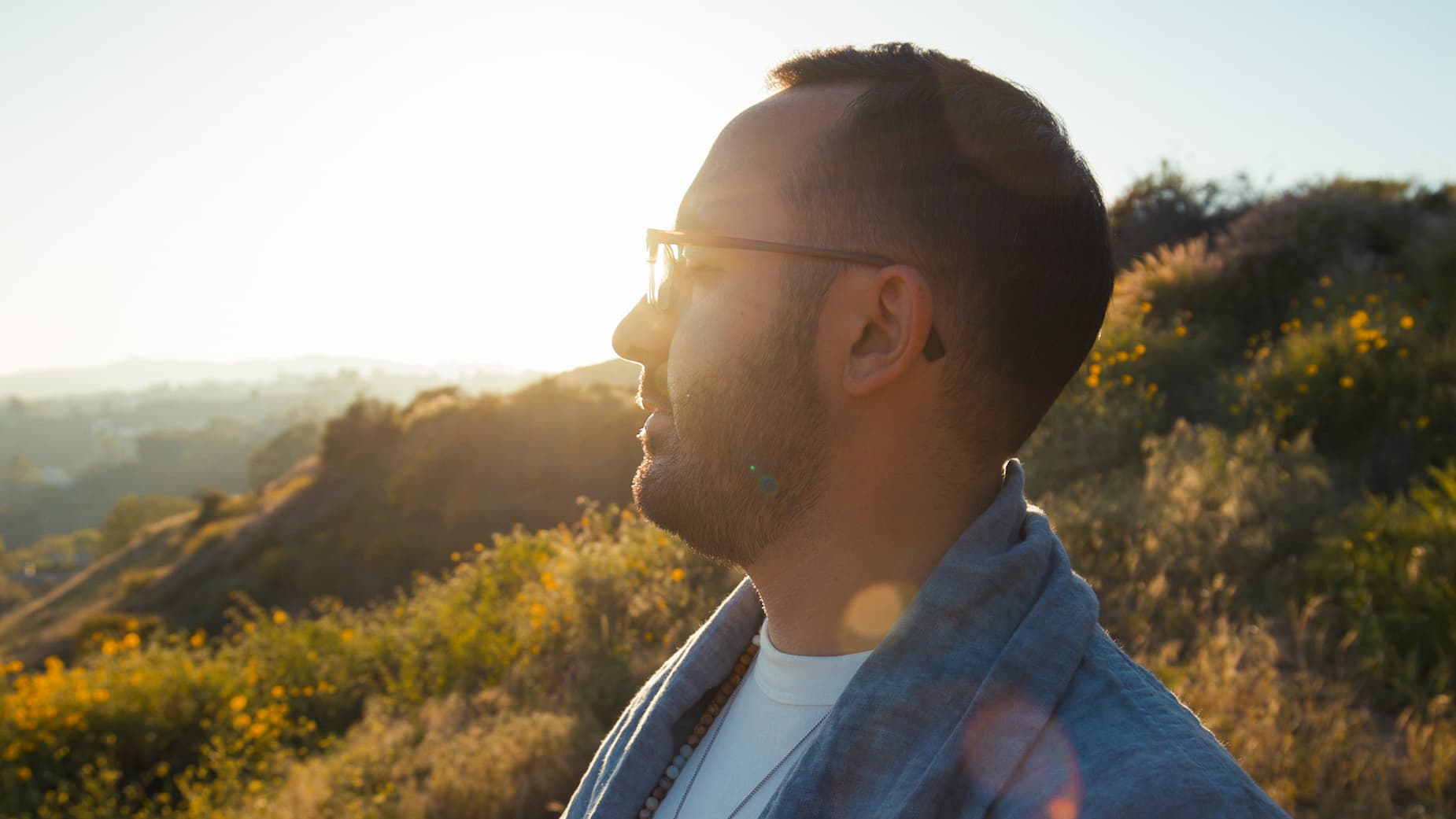 Dr. Cameron Martin looking out over a sunlit hillside at golden hour