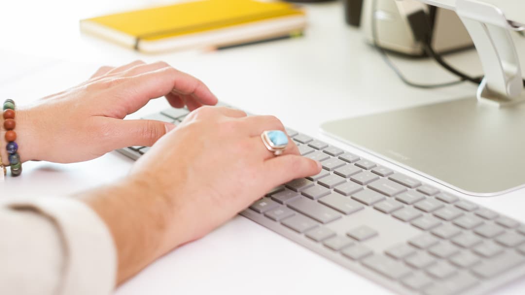 Hands typing on a keyboard at a desk